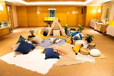 a living room filled with lots of furniture and pillows on top of a carpeted floor