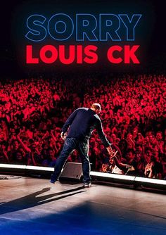 a man walking across a stage in front of a crowd with a sign that says sorry louis ck