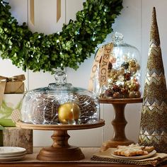 an assortment of holiday foods and decorations on a table with wreaths in the background