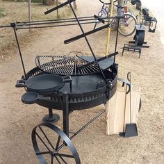 an outdoor grill is set up on the ground with other items around it and in front of some bicycles