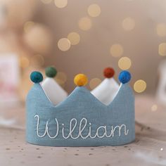 a small blue crown with the word william written on it's front and three little balls in the middle