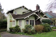 a green house with white trim on the front and side of it, surrounded by greenery