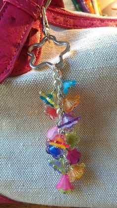 a purse with a chain attached to it and colorful charms hanging from the front pocket