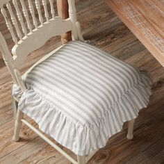 a white chair with a striped seat cover on top of it next to a wooden table