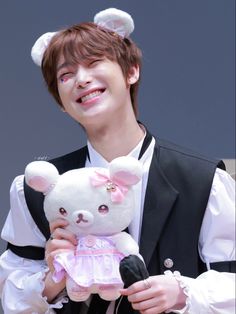 a young man holding a white teddy bear in his hands and smiling at the camera