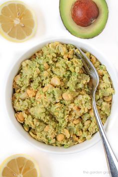 a bowl filled with guacamole next to sliced oranges and an avocado