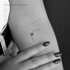 a woman's arm with a small flower tattoo on it