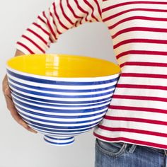 a woman holding a yellow and blue striped bowl