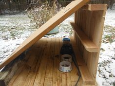 a beer bottle sitting on top of a wooden bench next to a snow covered field