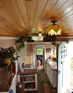 the inside of a tiny home with wood paneling and plants on the counter top