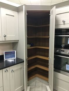 a kitchen with white cupboards and black counter tops is shown in this image, there is an open door to the pantry