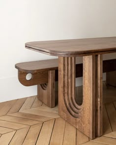 a wooden table with two benches sitting on top of it next to a white wall