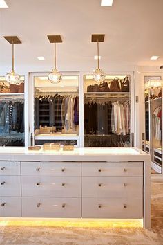 a large closet with lots of clothes hanging on the walls and two lights above it