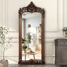 a large mirror sitting on top of a wooden floor next to a table and potted plant