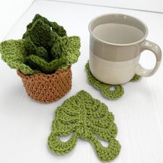 two crocheted coasters and a coffee cup with a plant in the middle