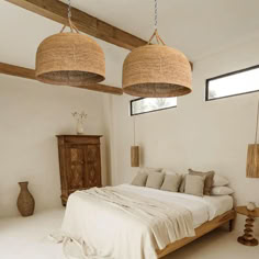 a bed sitting under two hanging lights in a bedroom