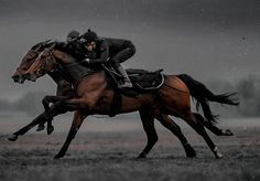 two jockeys are riding horses in the rain