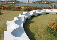 a curved bench sitting in the middle of a garden next to a body of water