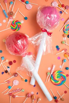 two lollipops on a pink background surrounded by candy