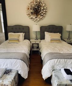 two twin beds in a bedroom with white linens and gray headboards on the wall