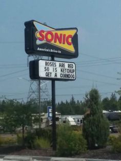 a sonic restaurant sign is shown in front of some trees and bushes on the side of the road