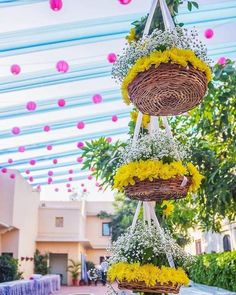 hanging baskets filled with yellow flowers and greenery in front of an outdoor party venue