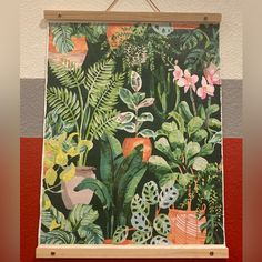 a painting hanging on a wall with plants and potted plants in front of it