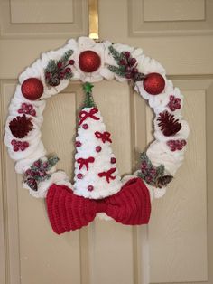 a knitted christmas wreath hanging on the front door