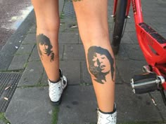 a person with tattoos on their legs standing next to a bike