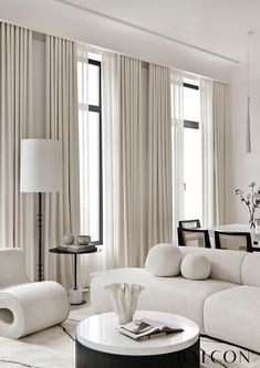 a living room with white furniture and curtains