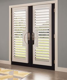 a living room with white shutters on the doors and wood flooring in front of it