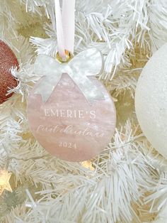 a personalized ornament hanging from a white christmas tree with ornaments around it