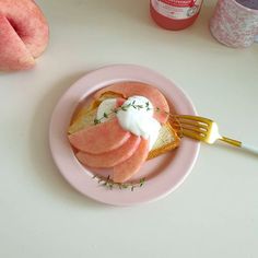 a pink plate topped with slices of fruit and cream on top of toasted bread