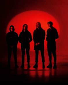 four people standing in front of a red light with the sun behind them and one person looking at the camera