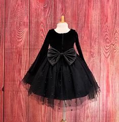 Little Darln Boutique  Our enchanting Knee Length flower girl dresses are sure to turn heads! This beautiful elegant sophisticated dress is handmade, the bodice consists of soft black velvet material, the back of the dress consists of a black satin detachable bow, with zipper for closure. The skirt consists of 4 Black layers of tulle with the top layer consisting with sowed in pearl beads. The fifth layer is made of lining with crinoline for fullness.  Dress Is Pictured with a petticoat NOT INCLUDED https://www.etsy.com/listing/1316417982/white-knee-length-petticoat-wedding?click_key=41cb8b0ae4587efa582b0a433f3f5e0cde12aec0%3A1316417982&click_sum=af1df37b&ref=shop_home_active_1 Visit our store, more items to come!  https://www.etsy.com/shop/LittledarlnBoutique?ref=profile_header CUSTOM MEA Christmas Wedding Flower Girl, Christmas Wedding Flowers, Burgundy Flower Girl Dress, Black Flower Girl Dress, Elegant Wedding Flowers, Toddler Girl Fall, Black Velvet Top, Velvet Christmas, Toddler Flower Girl Dresses