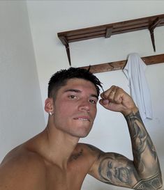 a man with tattoos on his arms and shoulder is looking at the camera while he brushes his hair