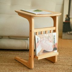 a magazine rack with magazines on it in front of a white couch and coffee table