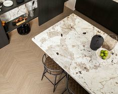 an aerial view of a kitchen with marble counter tops and black appliances in the background