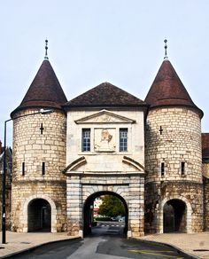 an old brick building with two towers and a clock on the front entrance door is shown