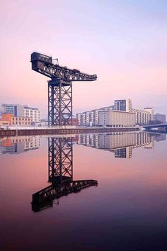 a large crane sitting on top of a body of water next to tall buildings in the background