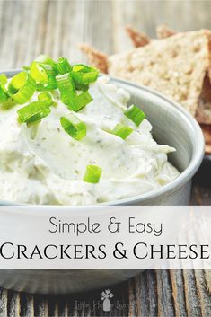 a white bowl filled with crackers and cheese on top of a wooden table next to bread