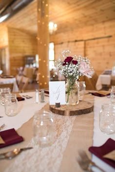 the table is set with place cards and flowers in vases on top of it