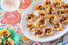 small appetizers are arranged on a plate next to wine glasses and plates with desserts