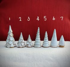 a row of white christmas trees sitting on top of a table next to a red pillow