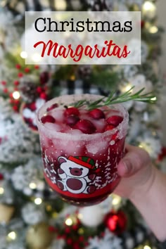 someone holding up a drink in front of a christmas tree with the words, christmas margaritas