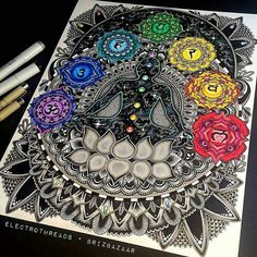 an intricate coloring book with flowers and numbers on the cover, surrounded by pens and markers