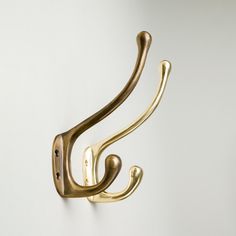 a pair of brass hooks on a white wall