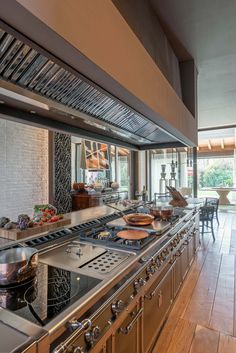 a kitchen with lots of counter space and stainless steel stove top ovens, pots and pans on the burners