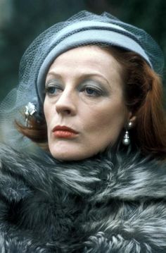 a woman with red hair wearing a gray hat and fur coat, looking off to the side