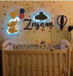 a baby crib in front of a wall with balloons and hot air balloons on it